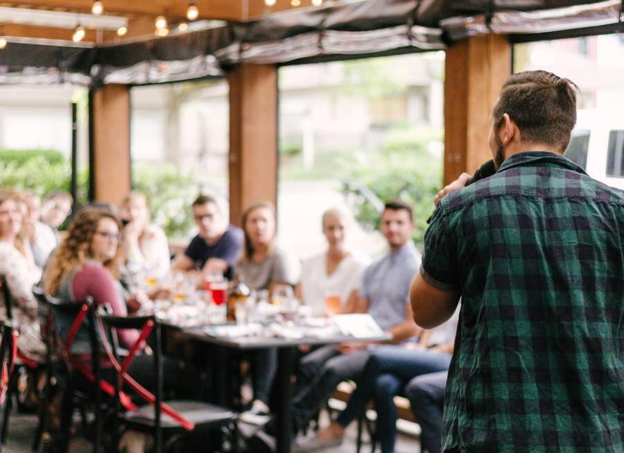 Giving a speech A speaker in front of a table with a small audience